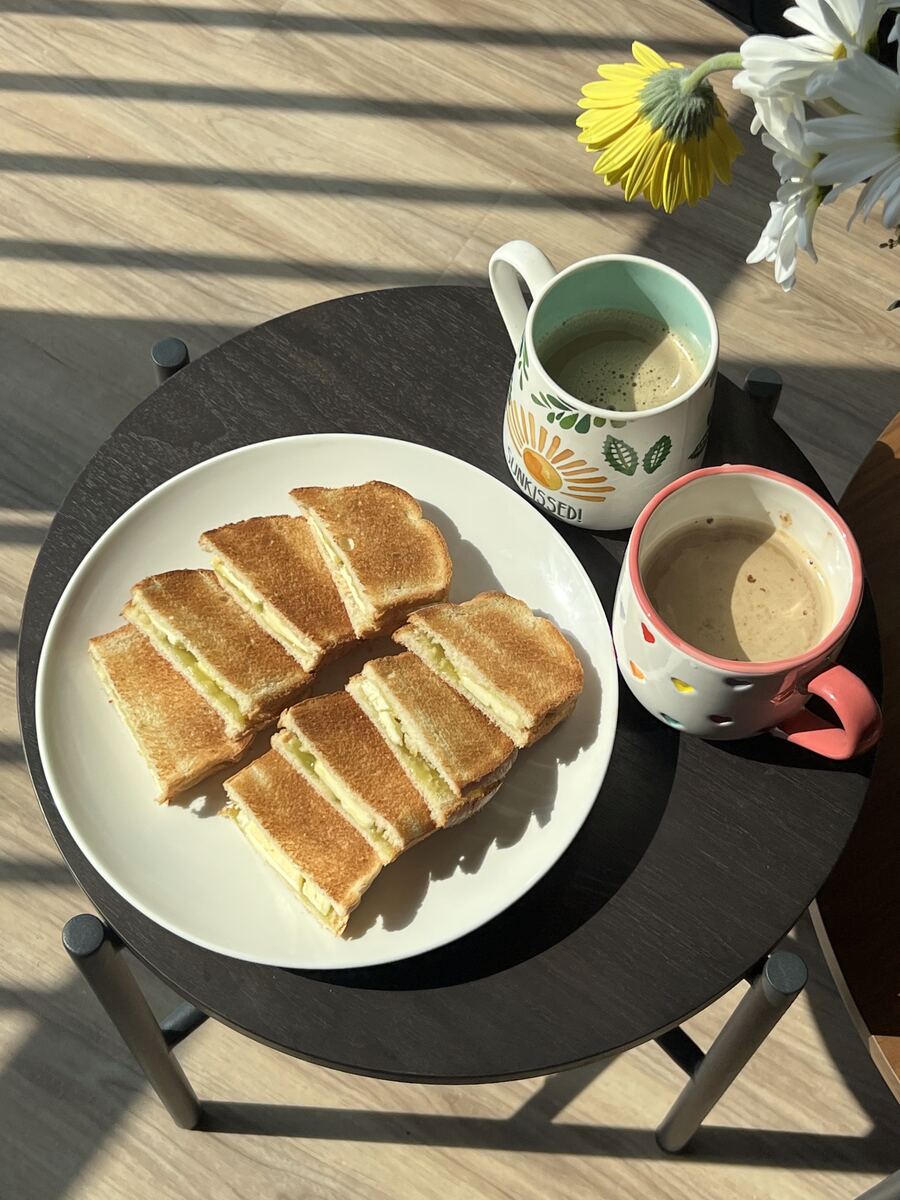Kaya toast cut into fingers on a plate beside a mug of coffee in morning light