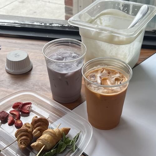 Iced ube latte and iced coffee beside croissants