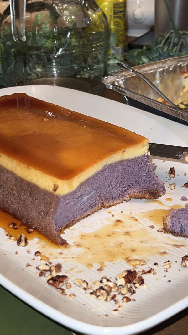 A slice cut from an ube leche flan showing the deep purple layer underneath
